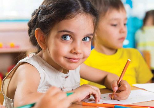 Pre-school Child smiling at camera as she draws